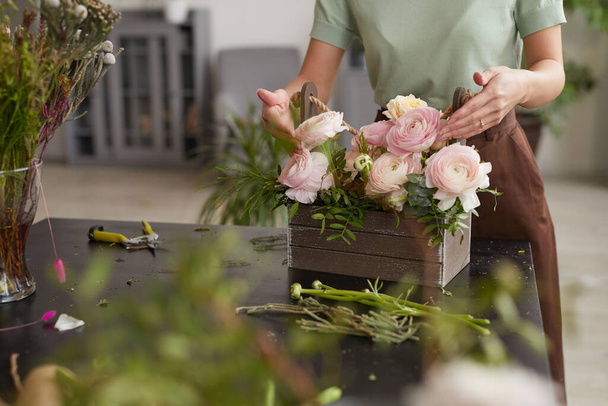 Retrato recortado de una joven irreconocible que arregla la composición floral con peonías rosadas mientras trabaja en el taller de floristas, espacio para copiar - Foto, imagen