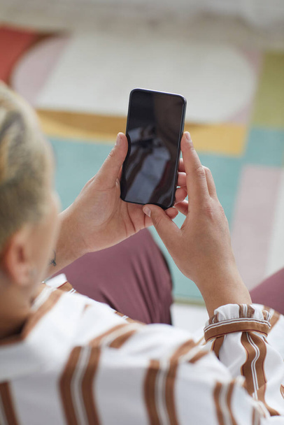 Vista vertical de alto ángulo en la mujer moderna que sostiene el teléfono inteligente con pantalla en blanco mientras usa la aplicación en línea, espacio de copia - Foto, Imagen