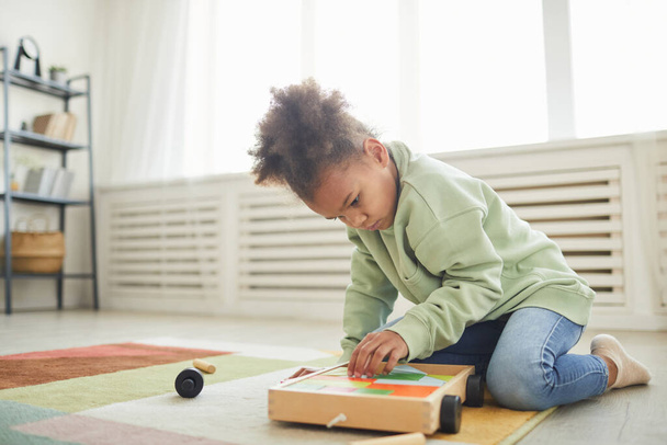 Портрет милої афро-американської дівчини, яка грає з іграшками на підлозі, копіюйте простір. - Фото, зображення