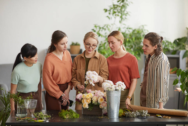 Front view portrait of diverse group of young people attending class on floral art in florists workshop - Фото, зображення