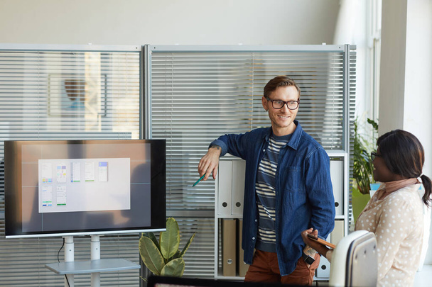 Περιηγηθείτε πορτρέτο του σύγχρονου ανθρώπου που στέκεται δίπλα στην ψηφιακή οθόνη, ενώ δίνει παρουσίαση στην ομάδα συνάντηση στο γραφείο ανάπτυξης της πληροφορικής, αντιγραφή χώρου - Φωτογραφία, εικόνα