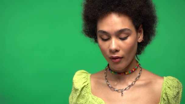 Zöld alapon izolált orvosi maszkot viselő afro-amerikai nő  - Felvétel, videó