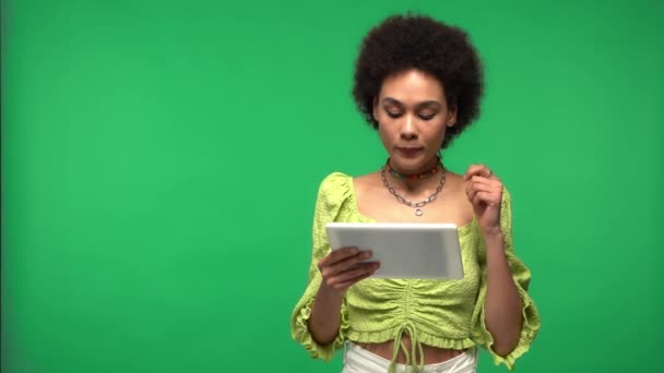 Afroamerikanerin mit Videoanruf auf digitalem Tablet isoliert auf grünem Grund  - Filmmaterial, Video