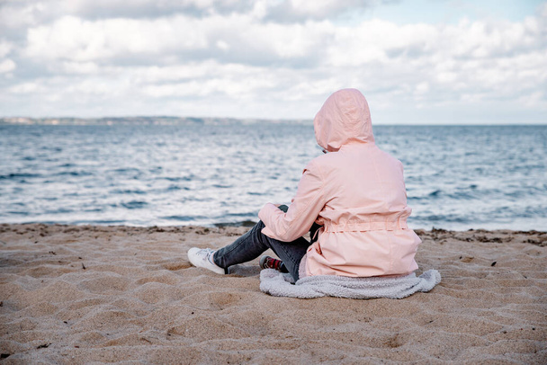 Mujer solitaria sentada en la arena de la playa - Foto, imagen