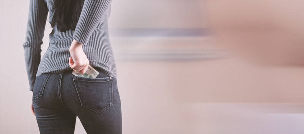 Woman hand putting money in jeans pocket - Zdjęcie, obraz