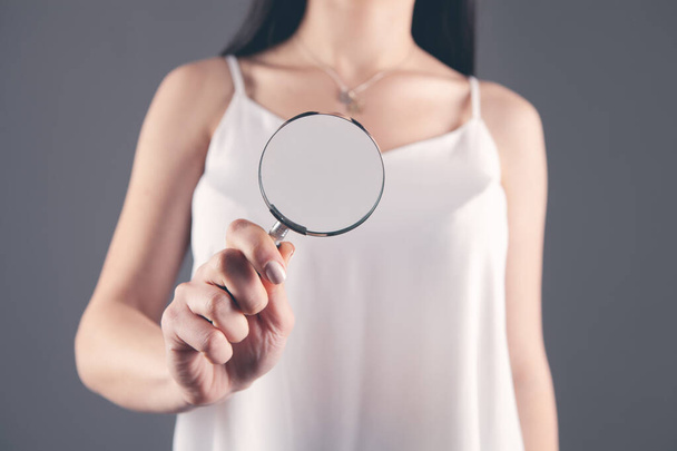 girl holding a magnifying glass in her hand and looking - Foto, imagen