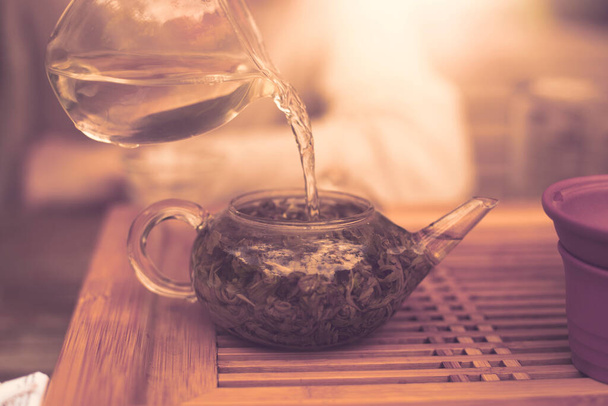Nalít horkou vodu do konvice plné zelených čajových lístků. Kvalitní fotografie - Fotografie, Obrázek