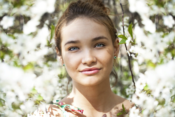 Beautiful girl standing near blooming trees in spring garden  - Fotografie, Obrázek