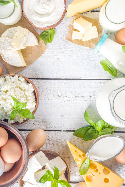 Набор различных свежих молочных продуктов - молоко, творог, сыр, яйца, йогурт, сметана, масло на деревянном фоне - Фото, изображение