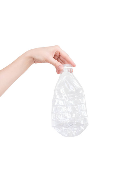 Mano femenina sosteniendo vacío botella de plástico triturado aislado en blanco. Residuos reciclables. Reciclaje, reutilización, eliminación de residuos, recursos, medio ambiente y ecología. - Foto, imagen