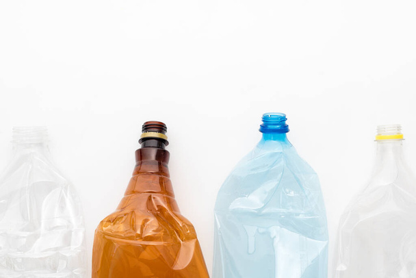 Diferentes tipos de garrafas de plástico esmagado no fundo branco. Copyspace para texto. Resíduos recicláveis. Reciclagem, reutilização, eliminação de lixo, recursos, ambiente e conceito de ecologia - Foto, Imagem