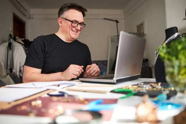 Merry jeweler in eyeglasses communicating with his customer online - Foto, Bild