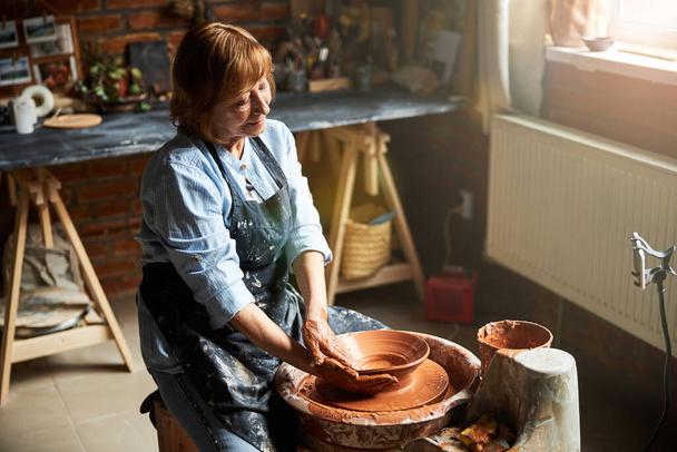Charming senior woman making pottery in workshop - Photo, Image