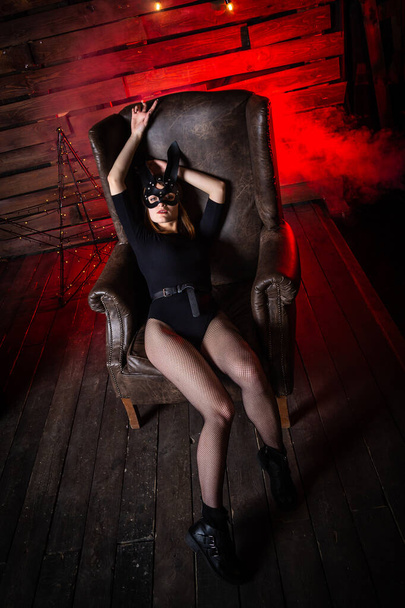 Seksowna kobieta w czarnej bieliźnie w skórzanej masce i akcesoriach BDSM Bunny. pozowanie na ciemnym tle. - Zdjęcie, obraz