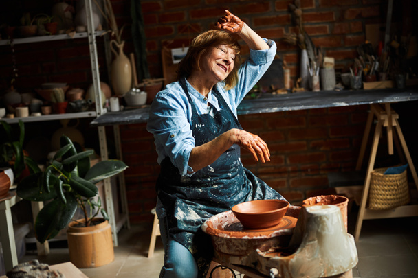 Joyful female potter working in pottery workshop - Photo, Image