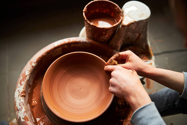 Potter hands making clay bowl on pottery wheel - Foto, afbeelding