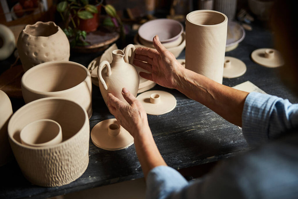 Keramikkünstlerin sitzt am Tisch mit Keramik in Werkstatt - Foto, Bild