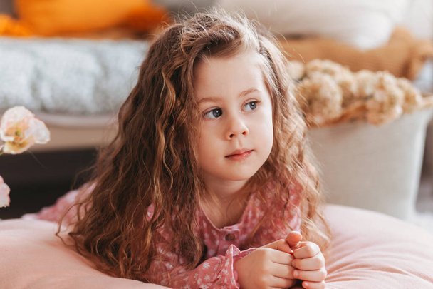 Ένα κοριτσάκι ξαπλώνει σ 'ένα μαξιλάρι στο παιδικό δωμάτιο. Ανάπαυση των παιδιών - Φωτογραφία, εικόνα