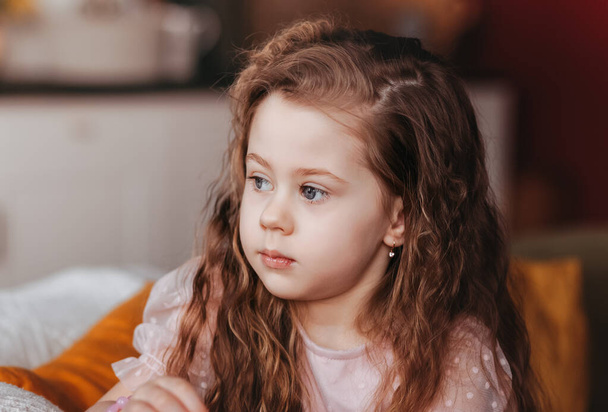 Πορτρέτο ενός μικρού κοριτσιού που ονειρεύεται από κοντά. μη κοιτάζοντας την κάμερα. - Φωτογραφία, εικόνα