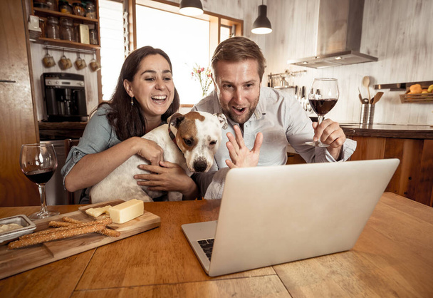 COVID-19 Stay safe Stay connected over winter holidays. Couple with dog pet in online video call cheering and celebrating christmas virtually with family during coronavirus second wave. - Foto, imagen