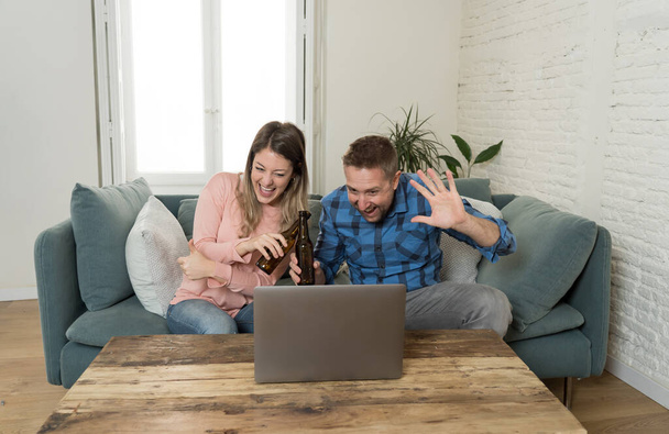 Life at home concept. Happy couple on laptop video calling friends and having an online party at home. Man and woman in video conference or live stream virtual event. Technology in the New Normal. - Foto, Imagen