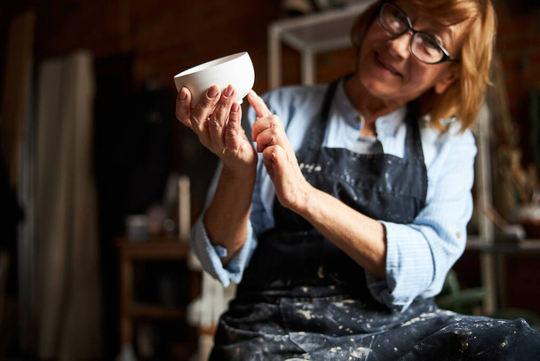 Keramikkünstlerin demonstriert Tonschale in Töpferwerkstatt - Foto, Bild