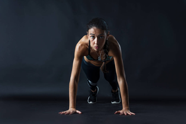 женщина, выполняющая фитнес-упражнения на черном фоне. - Фото, изображение
