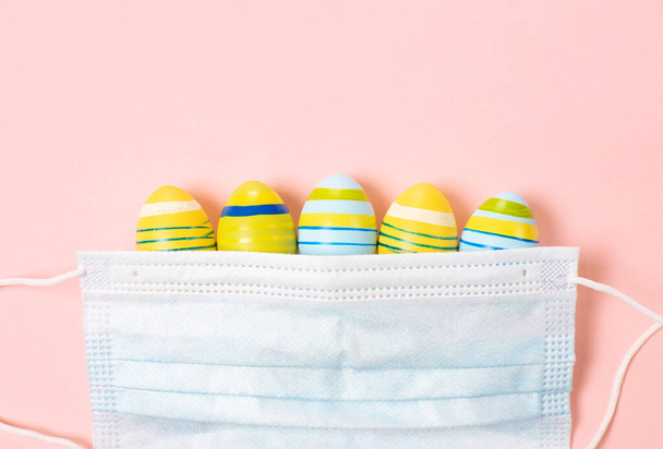 Easter Eggs 2021 with Coronavirus Defense Concept (COVID19). Velikonoční vajíčka pod lékařskou maskou na pastelové růžové. ochrana proti virům a karanténa. - Fotografie, Obrázek