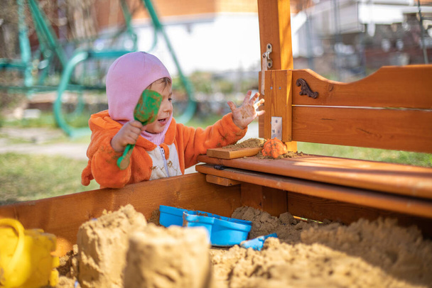 entzückendes Kleinkind beim Spielen im Sandkasten. Niedliches Kind im Fuchsschlafanzug spielt im Sand. Porträt eines glücklichen Babys. - Foto, Bild