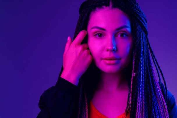 Fashion portrait of young woman with dreadlocks in neon light - 写真・画像