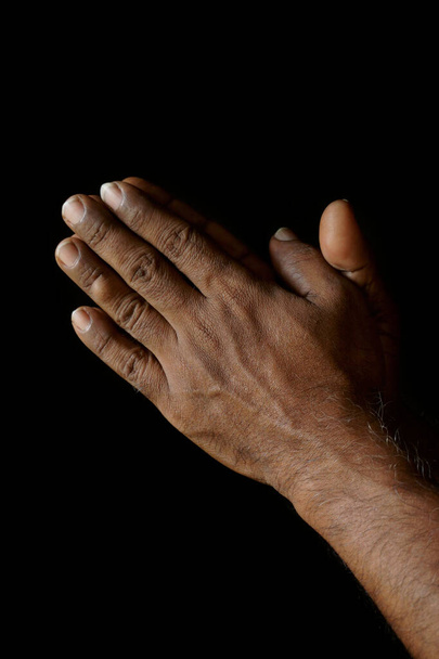 Biddende handen van Indiase katholieke man geïsoleerd op een zwarte achtergrond. - Foto, afbeelding