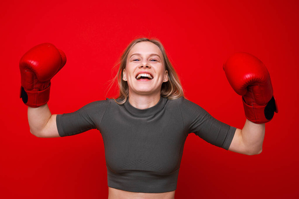Sportovní mladá žena v červených boxerských rukavicích je blázen kolem - Fotografie, Obrázek