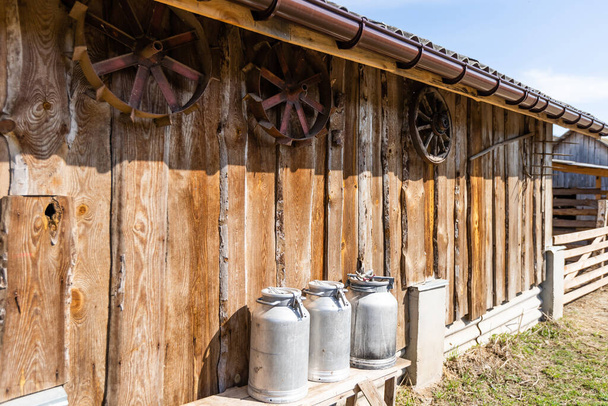 Una vieja lata de leche de metal, junto a un gran tronco de madera. Un tiro perfecto para describir la vida rural en una granja. - Foto, Imagen