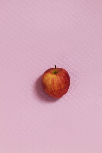 The vertical photo shows a picture of food. This apple is red in color. One apple. The apple is whole and in the skin - Fotó, kép