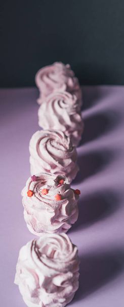 Verse marshmallows op een paarse achtergrond. Zephyr, meringue. Het concept van zelfgemaakt eten, snoepjes. Minimalisme, bovenaanzicht, flat lay, copyspace. - Foto, afbeelding