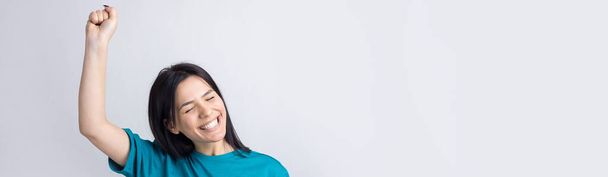 close-up portret van aantrekkelijk schreeuwen in winnen glimlachen met opgeheven vuisten jong ze haar meisje dragen jeans shirt kleding geïsoleerd op grijze achtergrond - Foto, afbeelding