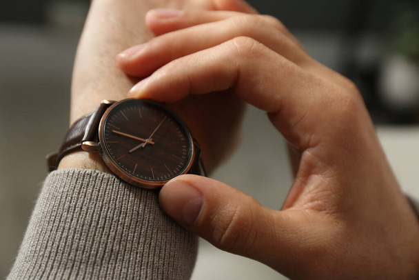 Man with luxury wrist watch on blurred background, closeup - Foto, afbeelding