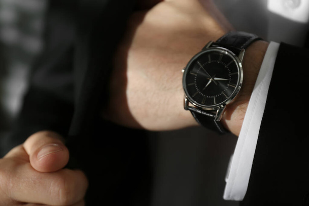 Businessman with luxury wrist watch on blurred background, closeup - Photo, image