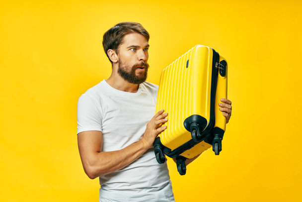 bärtiger Mann im weißen T-Shirt gelber Koffer Passagier isoliert Hintergrund - Foto, Bild