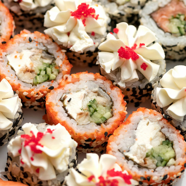 Rollos de sushi decorados con semillas de sésamo y caviar masago o tobiko. Set de Sushi de adentro hacia afuera. Diferentes tipos de rollos. Comida asiática o japonesa, cocina oriental. Primer plano. Vista superior. Enfoque suave - Foto, imagen