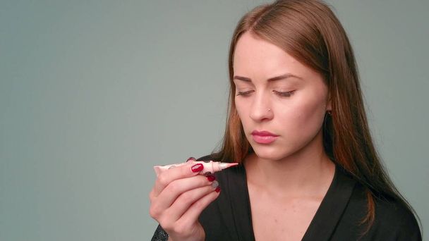 Young beautiful woman apply a lip gloss on her lips. Girl professional beauty vlogger or blogger applying lipstick cream to her lips - beauty concept close up. - Φωτογραφία, εικόνα