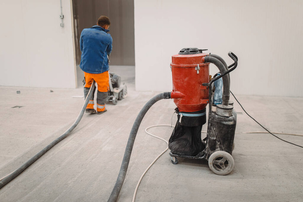 Työntekijät jauhaa betonilattia rakennustyömaalla. Valmistaa lattia polyuretaania laasti - Valokuva, kuva