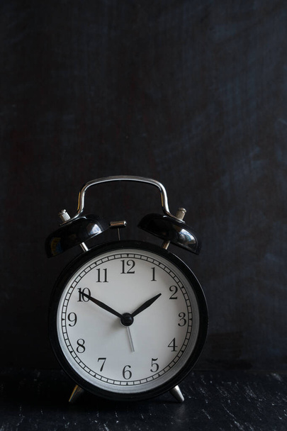 Reloj despertador retro en mesa de madera contra fondo negro - Foto, imagen