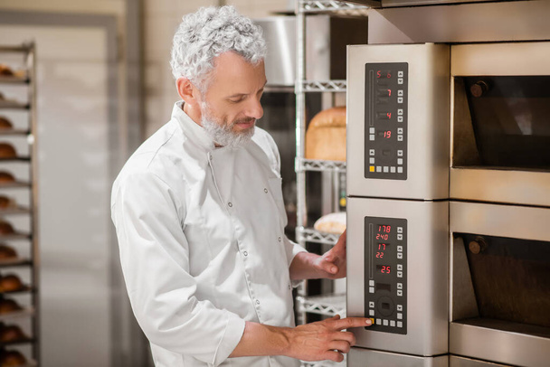 Man touching finger to control panel of oven - Foto, Bild