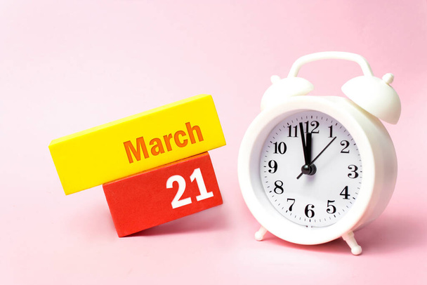 21 de marzo. Día 21 del mes, fecha del calendario. Reloj despertador blanco sobre fondo rosa pastel. Primavera mes, concepto del día del año - Foto, imagen