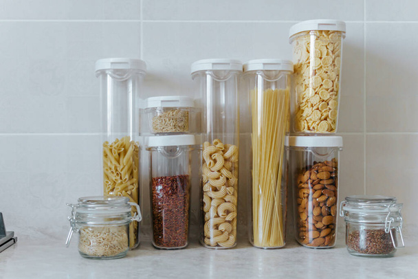 A variety of pasta, rice, cereals, nuts in containers-cans. The concept of proper convenient rational storage of food in the kitchen. - Fotoğraf, Görsel