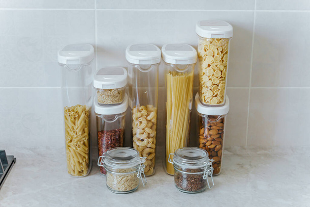 A variety of pasta, rice, cereals, nuts in containers-cans. The concept of proper convenient rational storage of food in the kitchen. - Zdjęcie, obraz