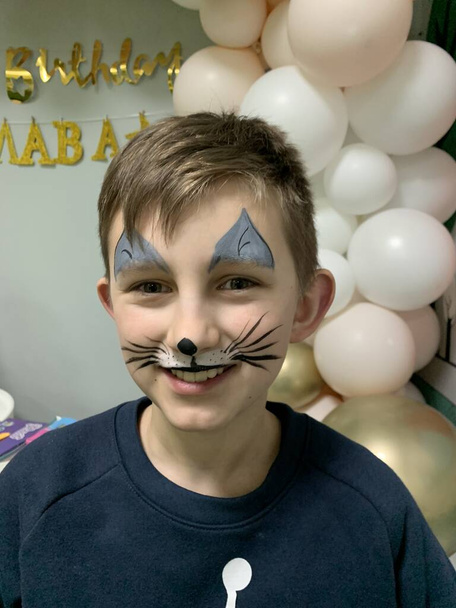 Junge mit gemaltem Katzengesicht lächelt auf der Geburtstagsparty  - Foto, Bild