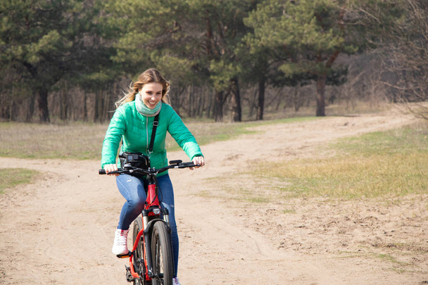 девушка ездит на электрическом велосипеде в весеннем лесу Украины в городе Днепр, на открытом воздухе отдыха - Фото, изображение