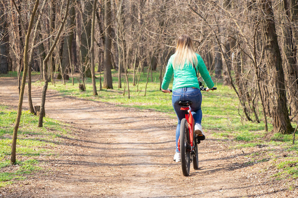 chica monta una bicicleta eléctrica en el bosque de primavera en Ucrania en la ciudad de Dnipro, recreación al aire libre - Foto, Imagen
